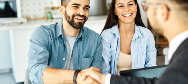 Real estate agent with couple shaking hands closing a deal and signing a contract
