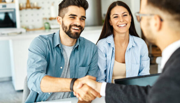 Real estate agent with couple shaking hands closing a deal and signing a contract